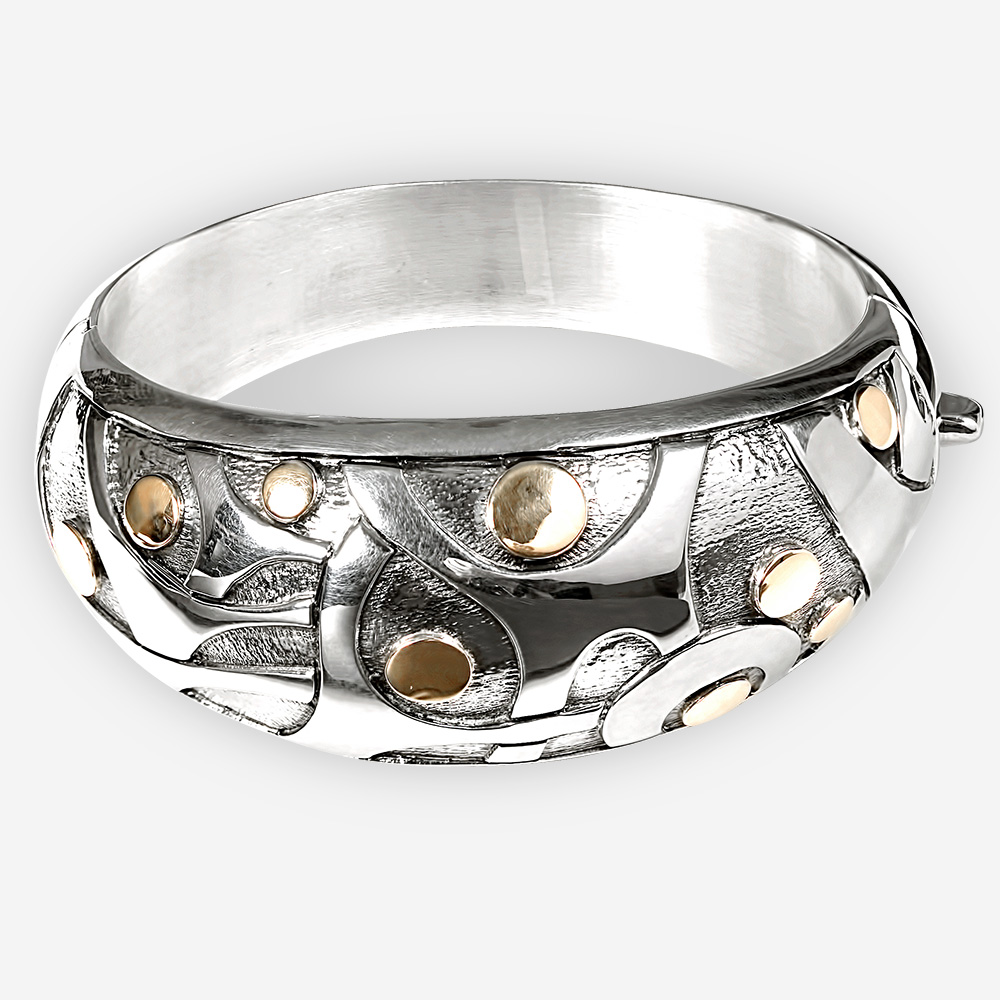 Silver bangle with blackened sterling silver and an embossed motif of abstract dancing little men with embossed14k gold heads.