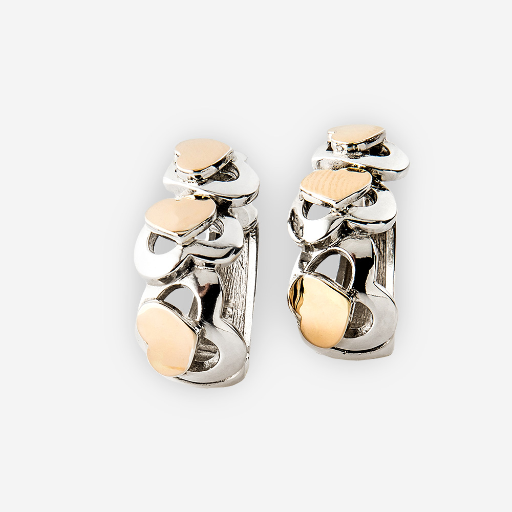 Two tone silver heart earrings. Huggie style with cutout heart design and overlapping gold hearts.
